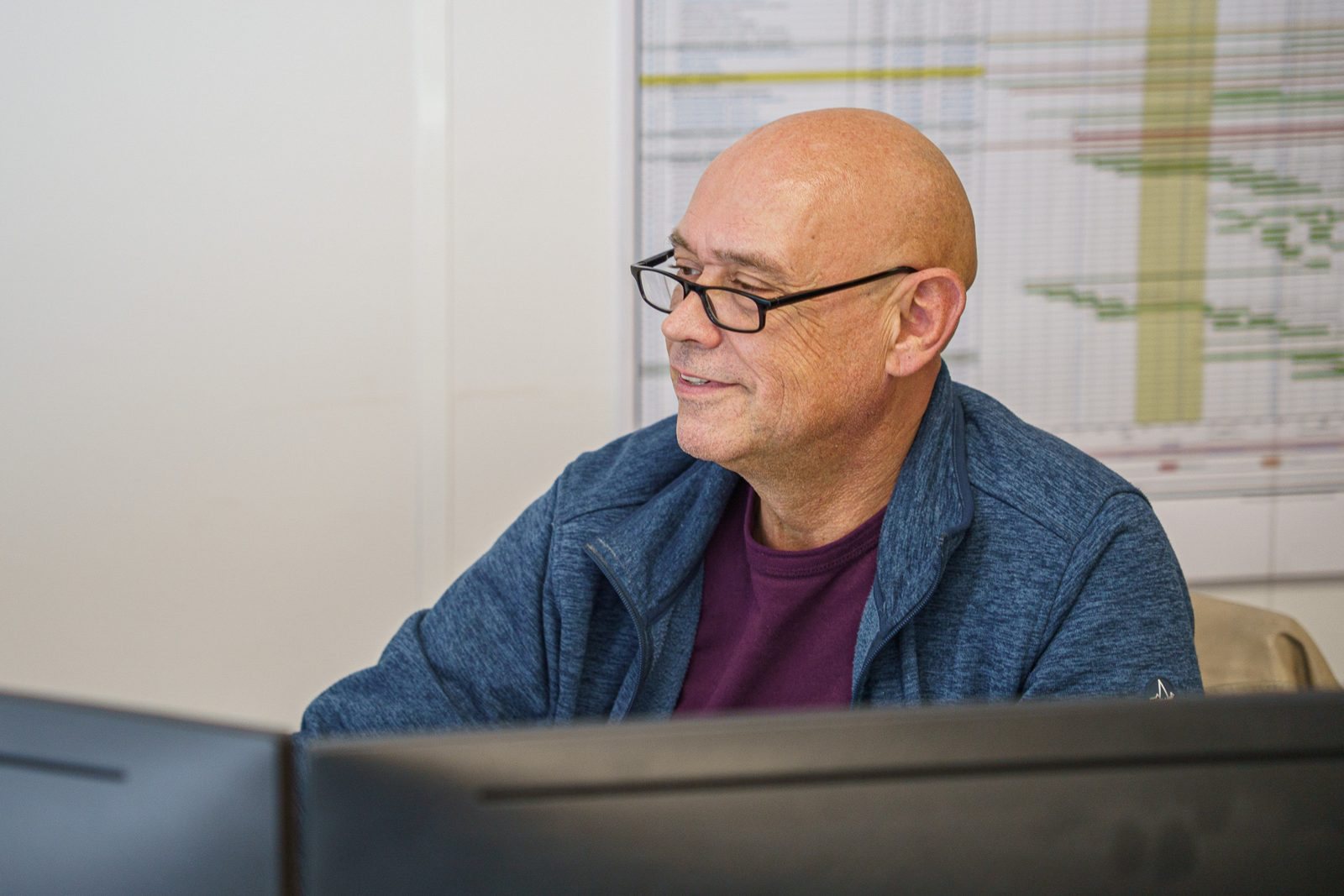 Projectleider Wim aan zijn bureau, met de projectplanning op de achtergrond